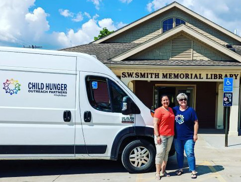 Linda Lamphere (left) and Mary Grace Collier-Kisler in front of white CHOP van and SW Smith Library